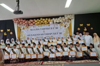 Acara Wisuda Tahfidz Juz 30 & Munaqosyah Tahap 2 di SD Islam Al Hidayah Pamulang berlangsung khidmat. Siswa-siswi menerima sertifikat dengan selempang kebanggaan, didampingi guru dan staf. Panggung berhias balon emas dan putih, mencerminkan semangat menghafal Al-Qur'an yang ditanamkan sekolah.
