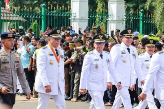 Wali Kota dan Wakil Wali Kota Tangerang Selatan, Benyamin Davnie dan Pilar Saga Ichsan, turut serta dalam prosesi seremonial bersama para pejabat lainnya. Mengenakan seragam putih dan atribut resmi, mereka melangkah tegap dalam acara yang dihadiri oleh banyak pihak.