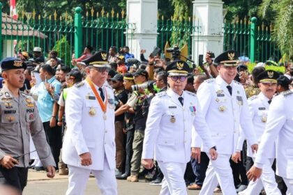 Wali Kota dan Wakil Wali Kota Tangerang Selatan, Benyamin Davnie dan Pilar Saga Ichsan, turut serta dalam prosesi seremonial bersama para pejabat lainnya. Mengenakan seragam putih dan atribut resmi, mereka melangkah tegap dalam acara yang dihadiri oleh banyak pihak.