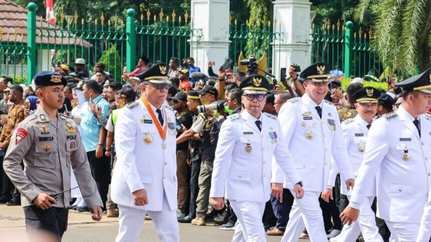 Wali Kota dan Wakil Wali Kota Tangerang Selatan, Benyamin Davnie dan Pilar Saga Ichsan, turut serta dalam prosesi seremonial bersama para pejabat lainnya. Mengenakan seragam putih dan atribut resmi, mereka melangkah tegap dalam acara yang dihadiri oleh banyak pihak.
